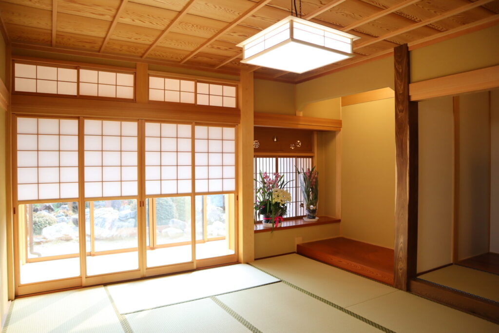 畳と障子が広がる和室。床の間に花が飾られ、木の天井と柔らかな光が静かな雰囲気をつくる。
