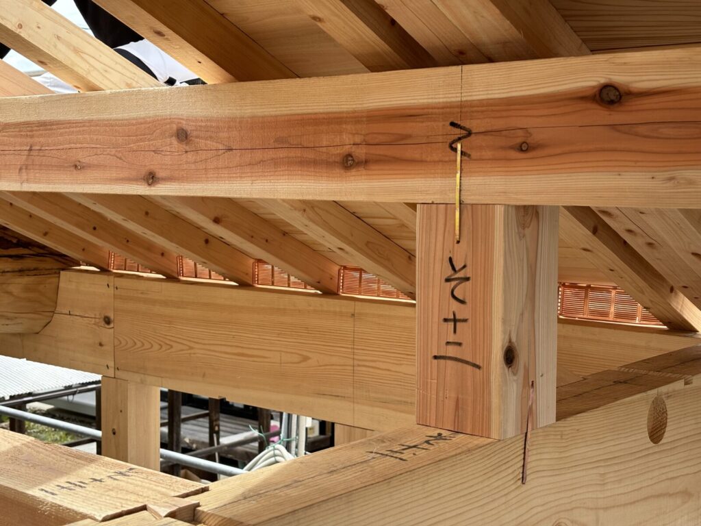 屋根の木組みが見える建築中の構造。梁や垂木が丁寧に組まれ、伝統的な木造の技が表れる。