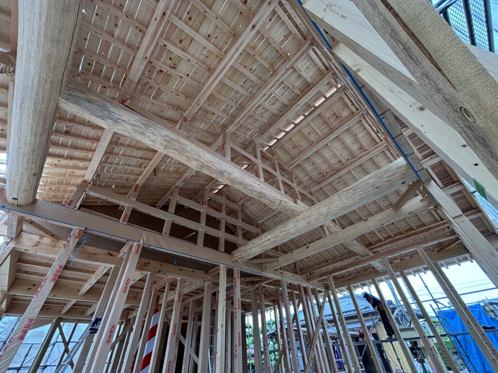 木組みの構造が現れる建築中の室内。太い梁や柱、天井の木材が美しく組まれ、伝統的な木造の技が見える。