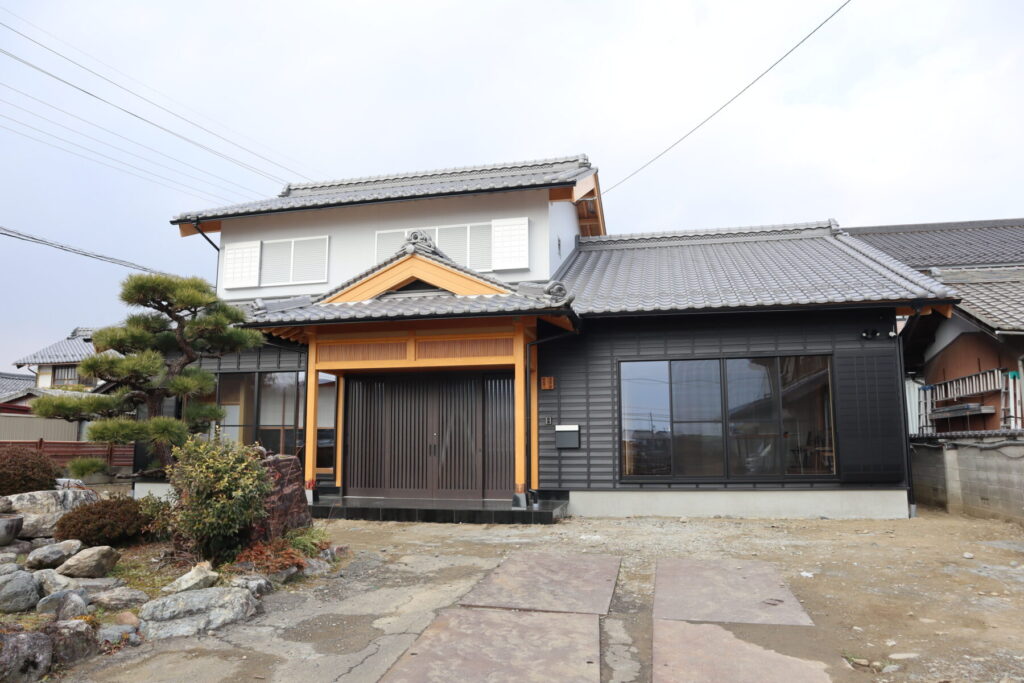 瓦屋根と木の意匠が美しい和風住宅の外観。手入れされた庭木と石垣、竹垣が佇む落ち着いた住まいの景色。