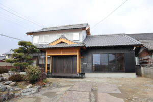 瓦屋根と木の意匠が美しい和風住宅の外観。手入れされた庭木と石垣、竹垣が佇む落ち着いた住まいの景色。